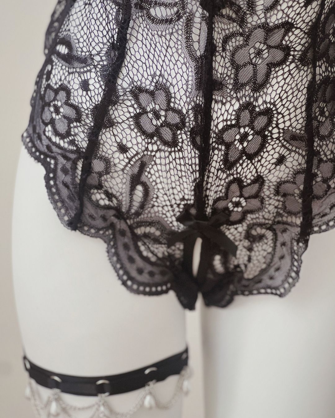 Black lace garment on a mannequin with a neutral background