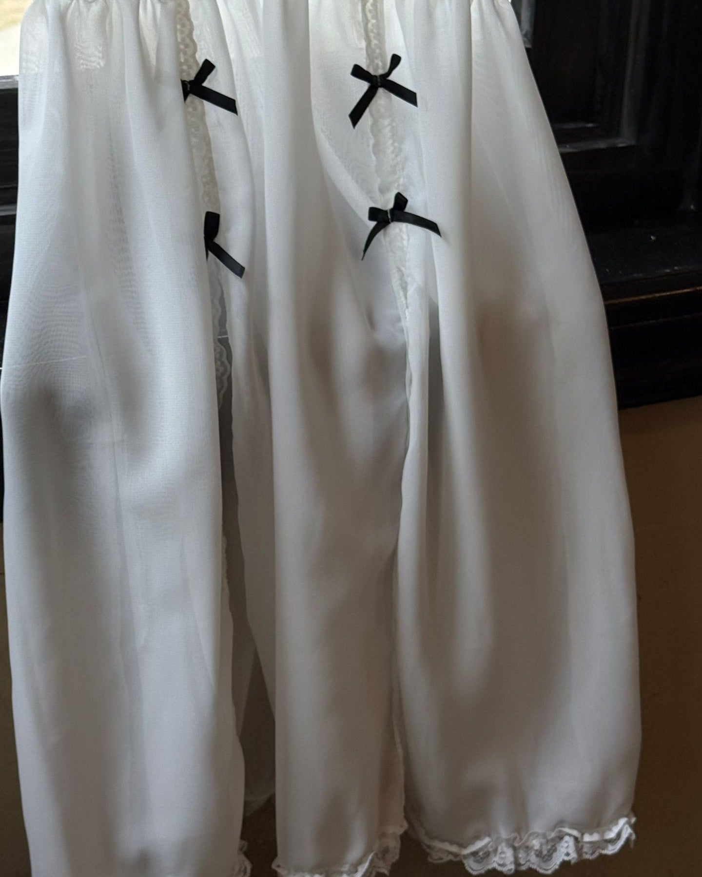 White lace-trimmed dress with black bows on a dark background