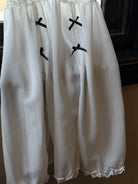 White lace-trimmed dress with black bows on a dark background