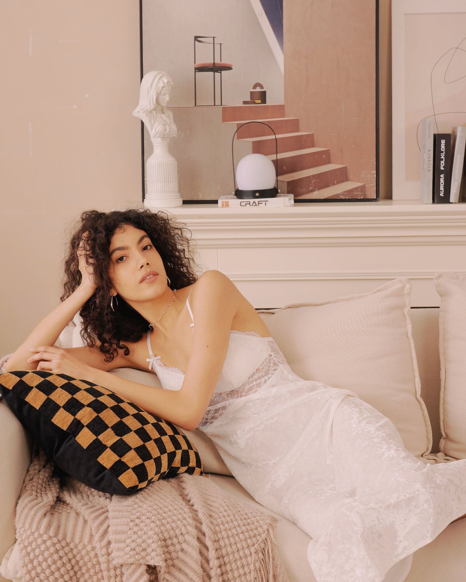 Model lounging on a beige couch in the white Snowkiss Nightdress. Perfect for soft mornings and romantic evenings at home.