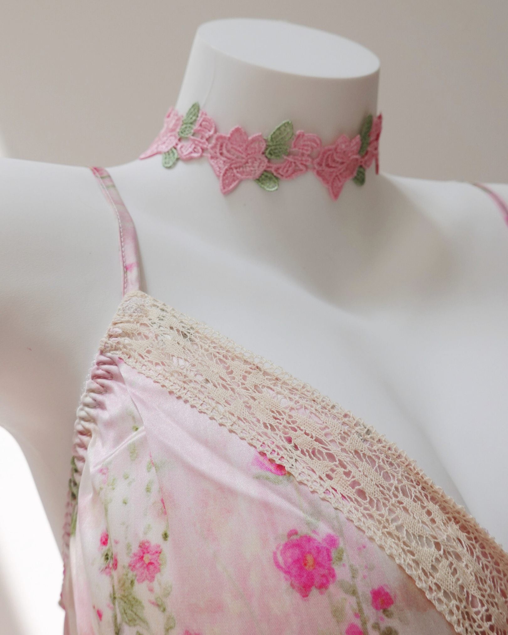 Mannequin wearing a floral dress with a matching pink lace choker on a white background