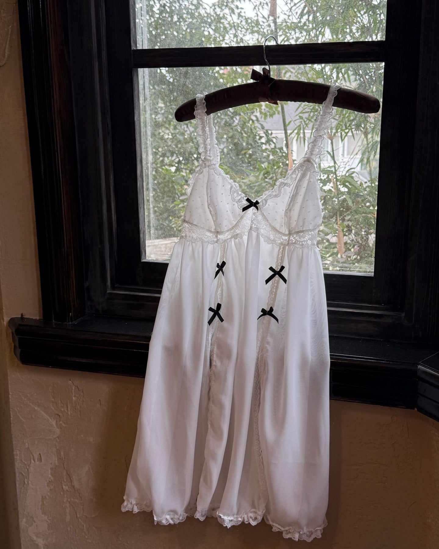 White dress with black accents on a hanger in front of a window