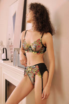 Side view of model in embroidered floral lingerie set with sheer mesh and garter belt – detailed floral textures on black base