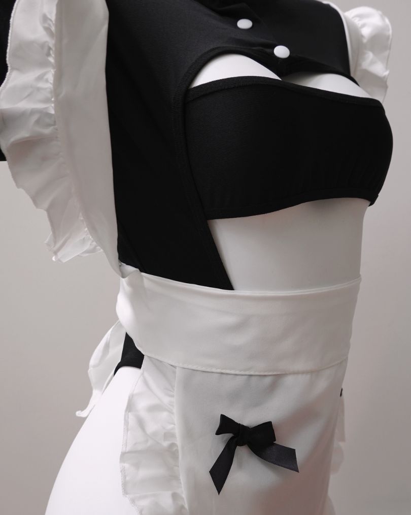 Black and white maid lingerie with a bow detail on a plain background
