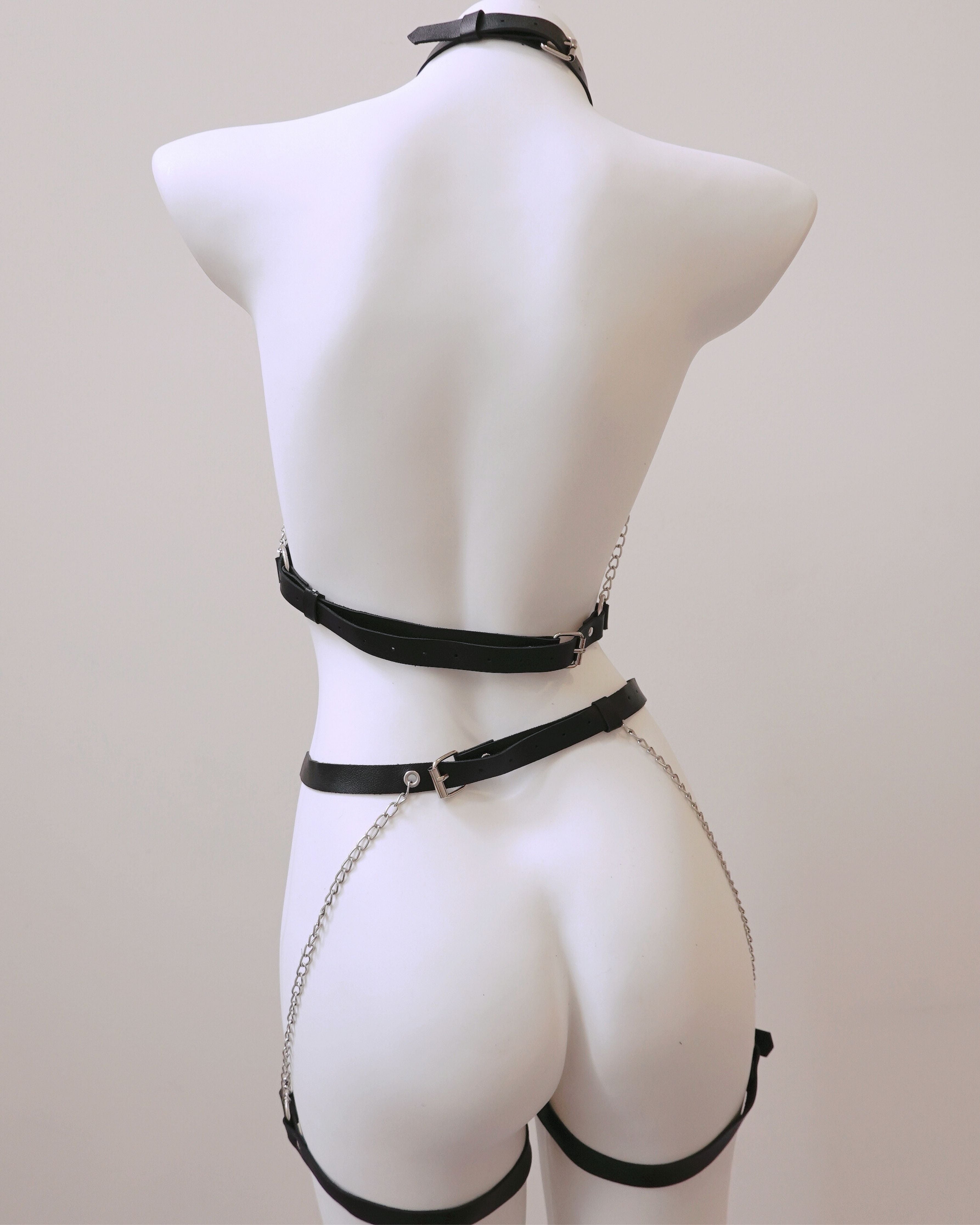 Black leather harness on a mannequin against a plain background