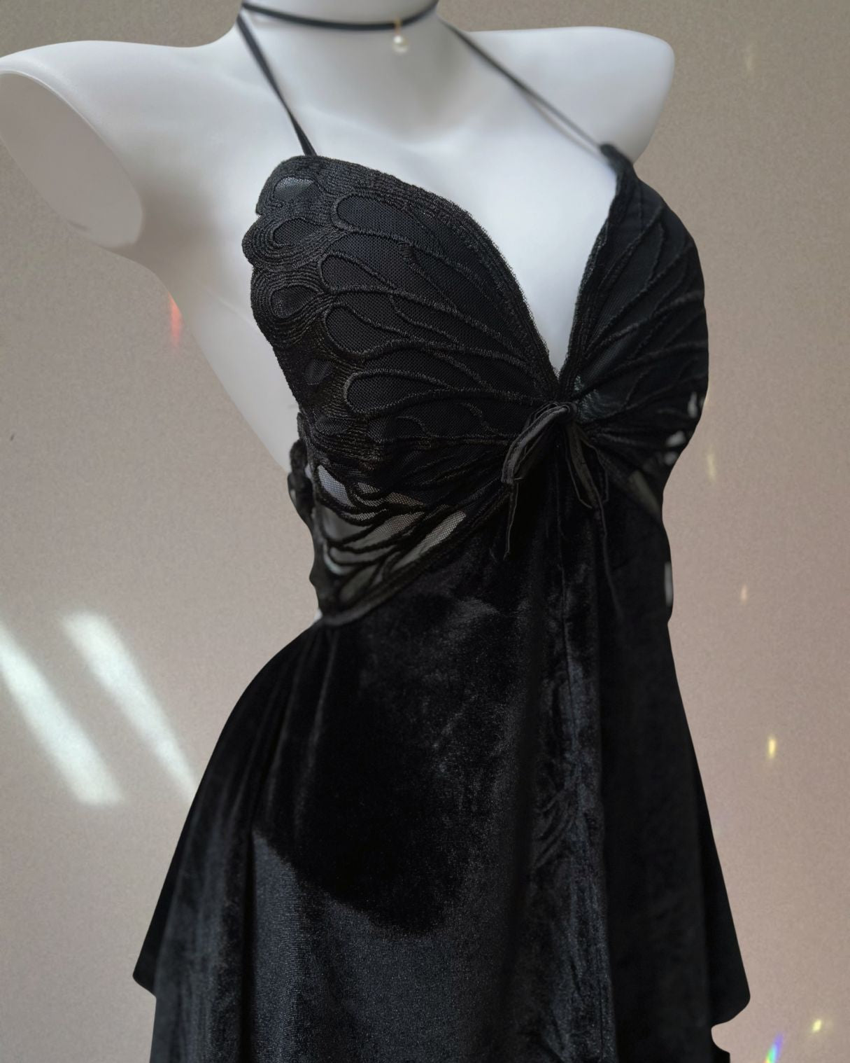 Black dress with butterfly wings on a mannequin against a neutral background