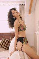 Smiling model in colorful floral embroidered bra and sheer black lingerie set with garter belt – lightweight and romantic design by FairyBerry