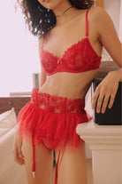 Model wearing a red embroidered lingerie set with sheer mesh bra and high-waisted tulle garter belt by FairyBerry