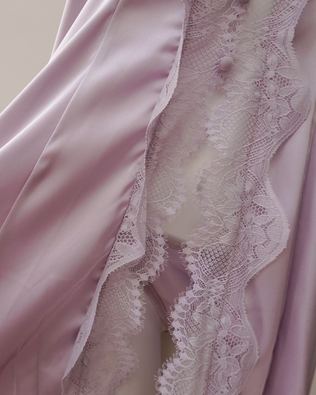 Pink satin fabric with lace trim on a neutral background