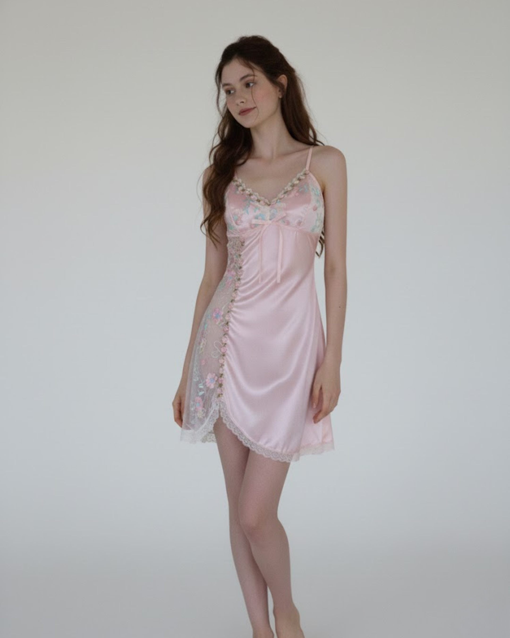 Woman wearing a pink fairyberry satin nightgown against a plain background
