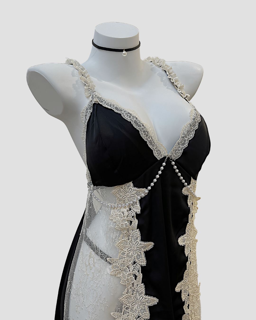 Black dress with white lace detailing on a mannequin against a white background