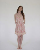Woman wearing a pink floral nightgown against a plain background