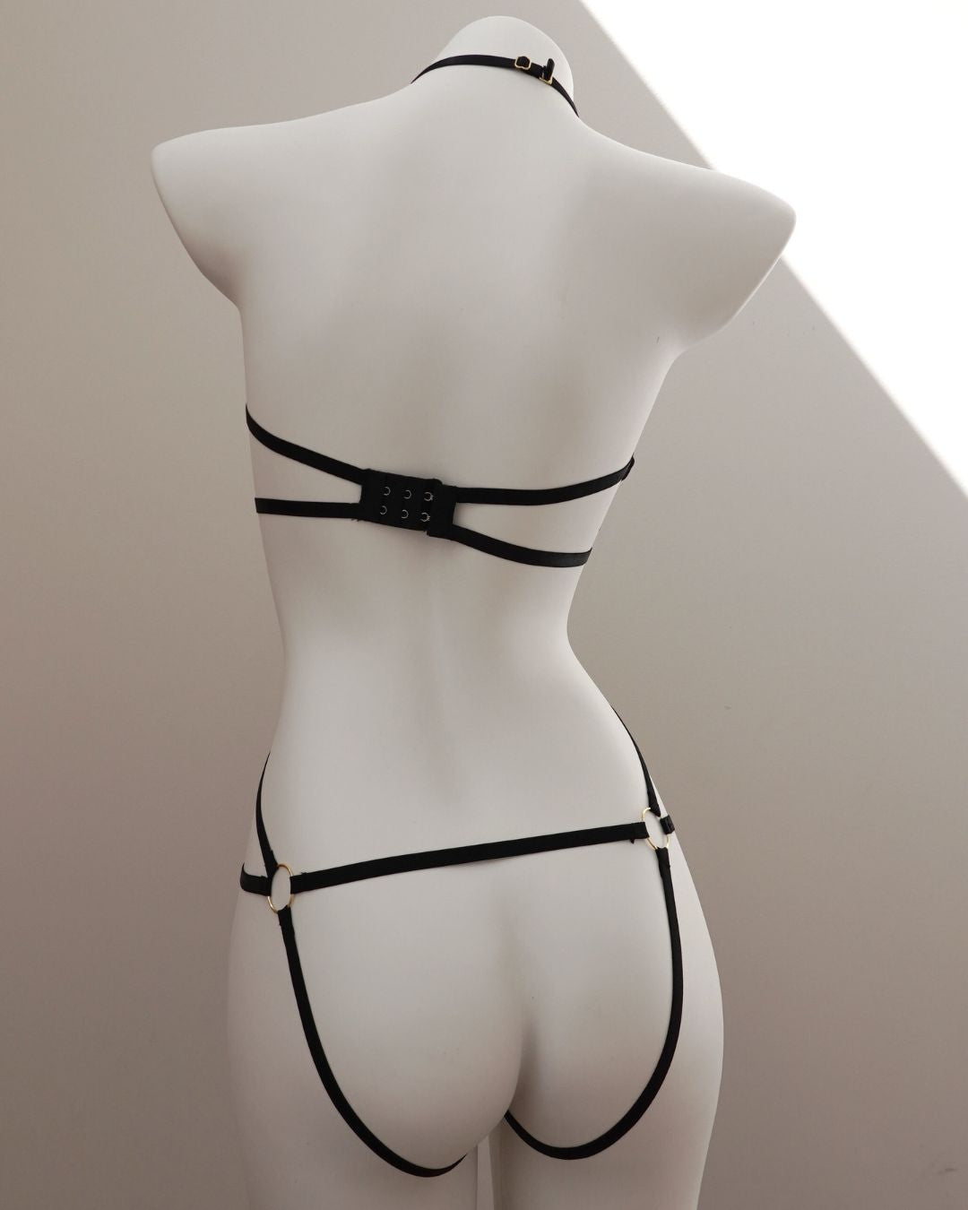 Black bondage harness lingerie set on a mannequin against a neutral background