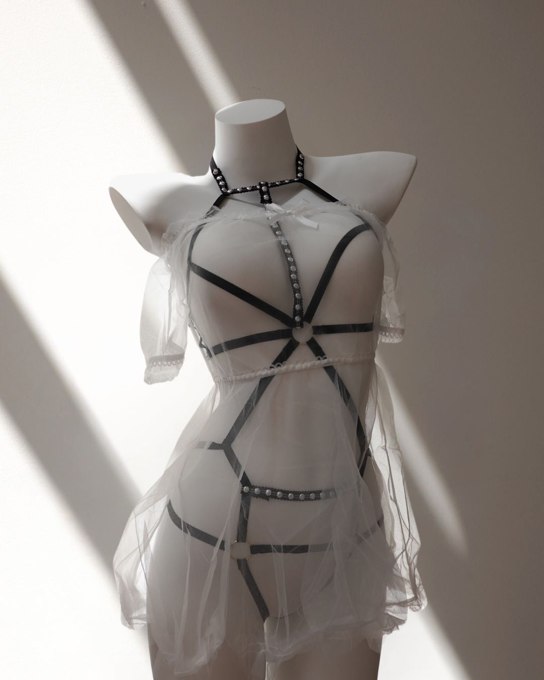 White lace dress with black bondage lingerie accents on a mannequin against a neutral background