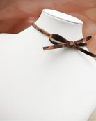 White shirt with a brown leather tie on a mannequin against a blurred background