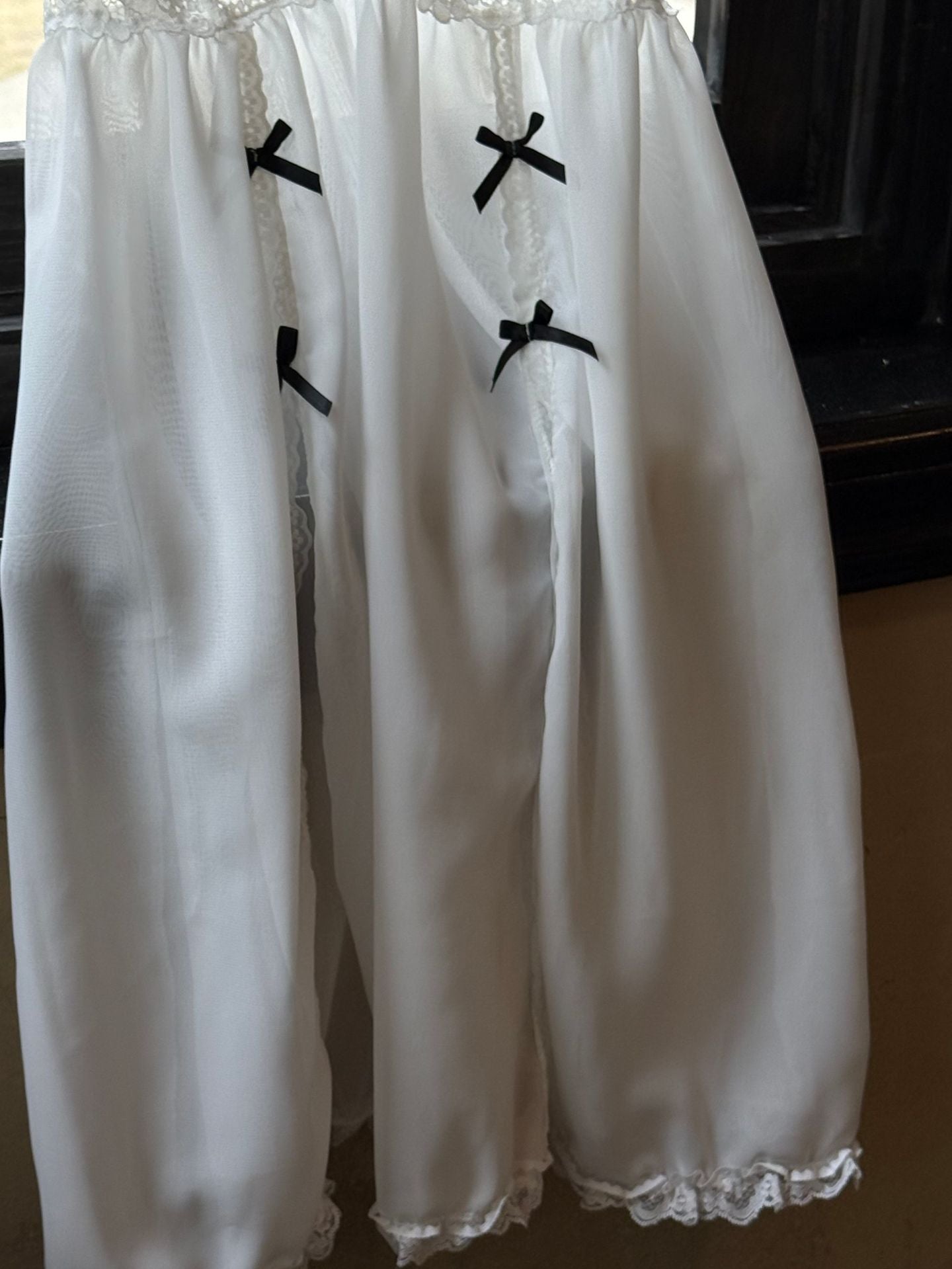 White lace-trimmed dress with black bows on a dark background