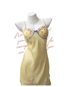 Mannequin wearing a yellow nightgown with floral embroidery on a white background