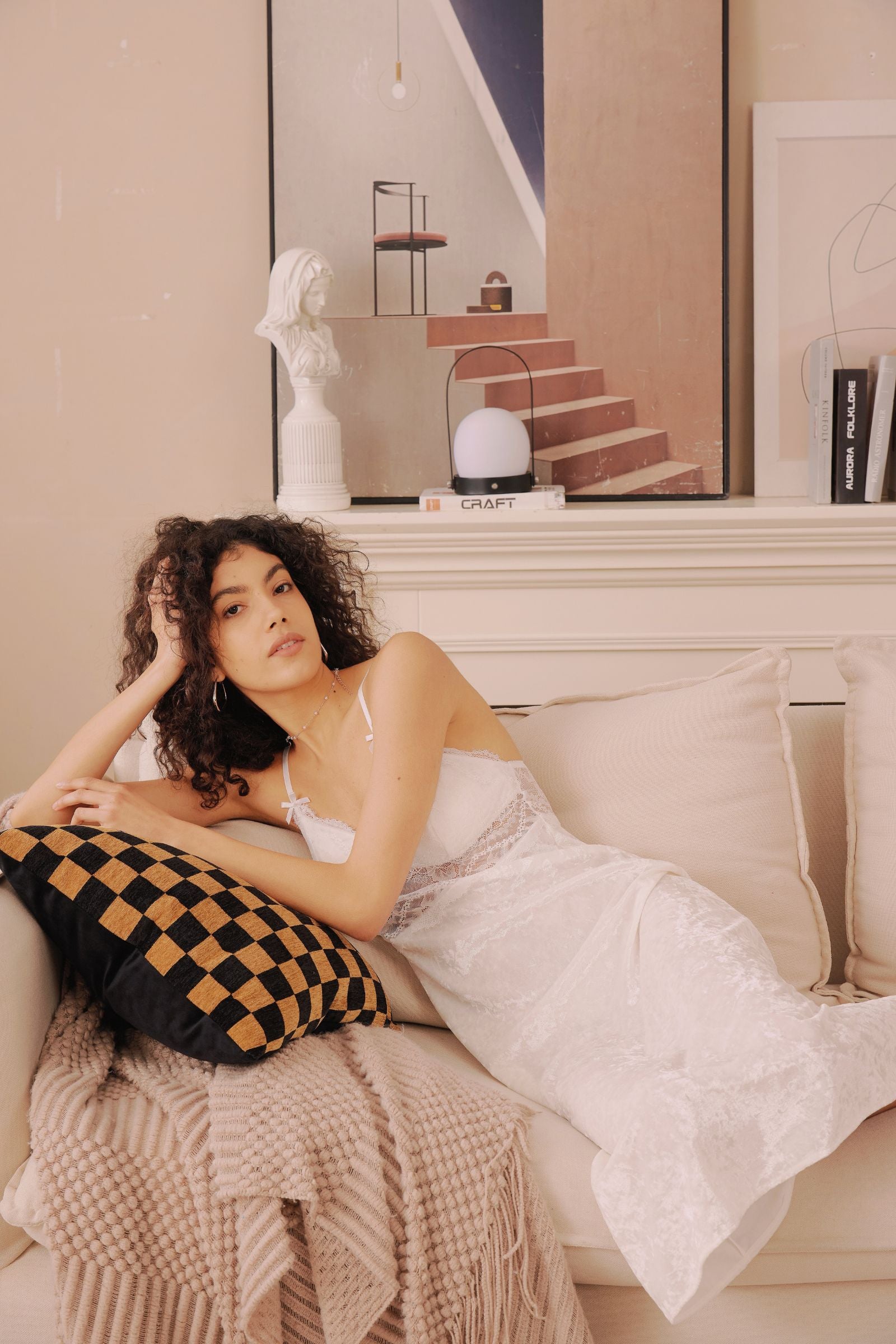 Model lounging on a beige couch in the white Snowkiss Nightdress. Perfect for soft mornings and romantic evenings at home.
