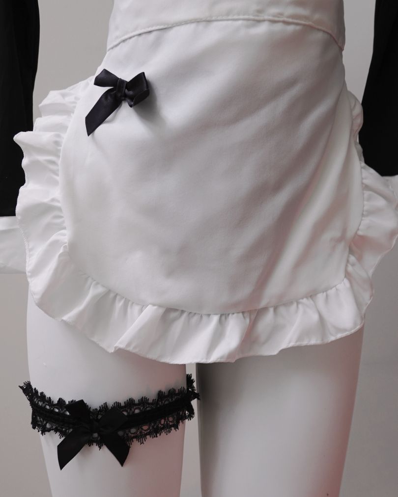 White apron lingerie with black bow and lace garter on a neutral background