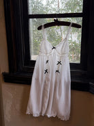 White dress with black accents on a hanger in front of a window