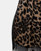 Close-up of a leopard print garment featuring a tan and black animal pattern with sheer black mesh overlay and a ruffled hem.