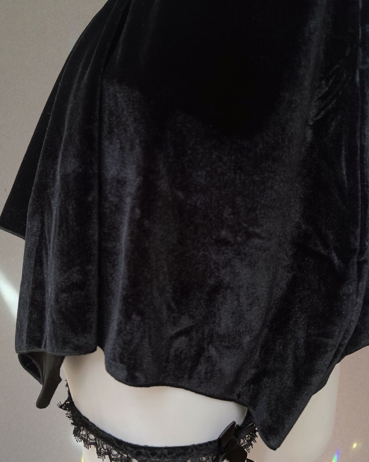 Black velvet garment on a mannequin with a plain background
