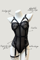 front view of  Ravenbite Bodysuit in black mesh with skull lace cups and built-in garter straps. Strappy and structured silhouette.