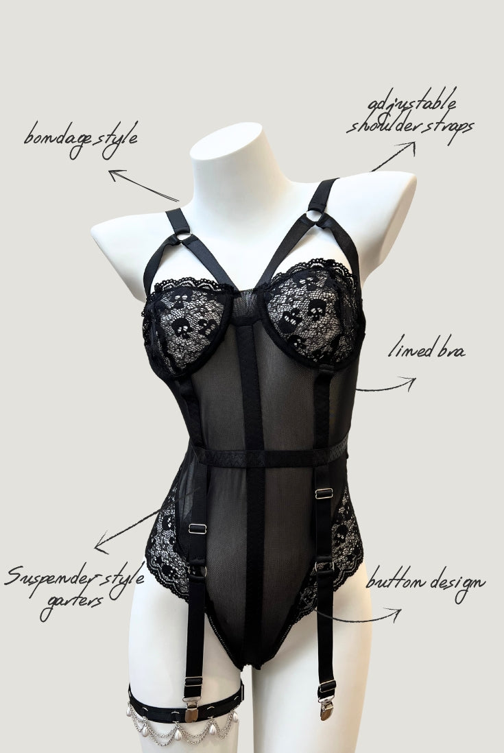 front view of  Ravenbite Bodysuit in black mesh with skull lace cups and built-in garter straps. Strappy and structured silhouette.