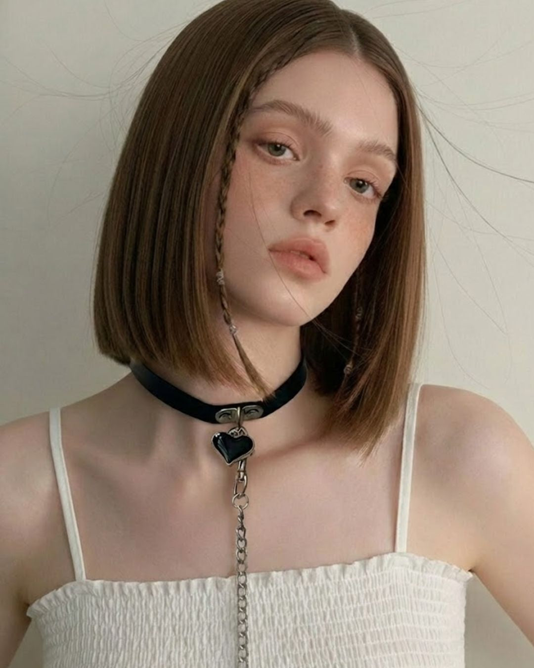 Woman wearing a black choker with a pendant against a neutral background