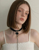 Woman wearing a black choker with a pendant against a neutral background