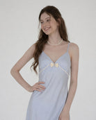 Woman wearing a light blue dress with a bow detail on a white background